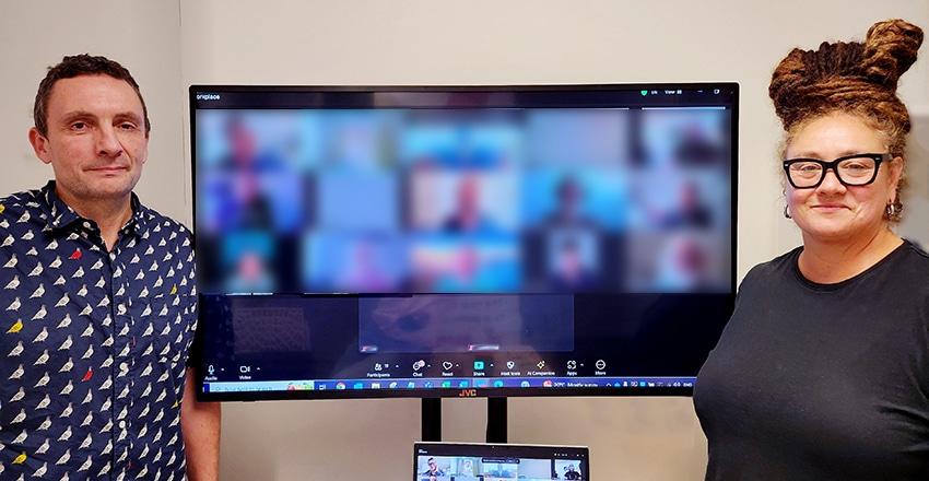 Two people standing in front of a large screen